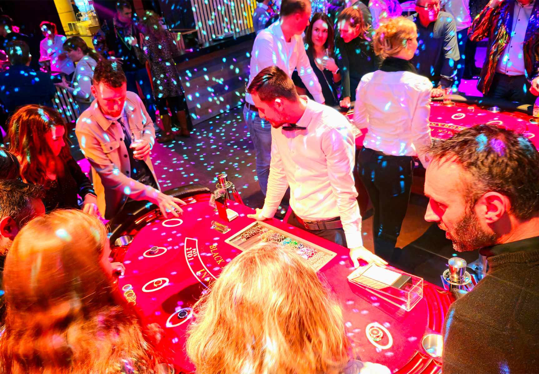 Gasten spelen aan twee blackjack speeltafels met croupiers.