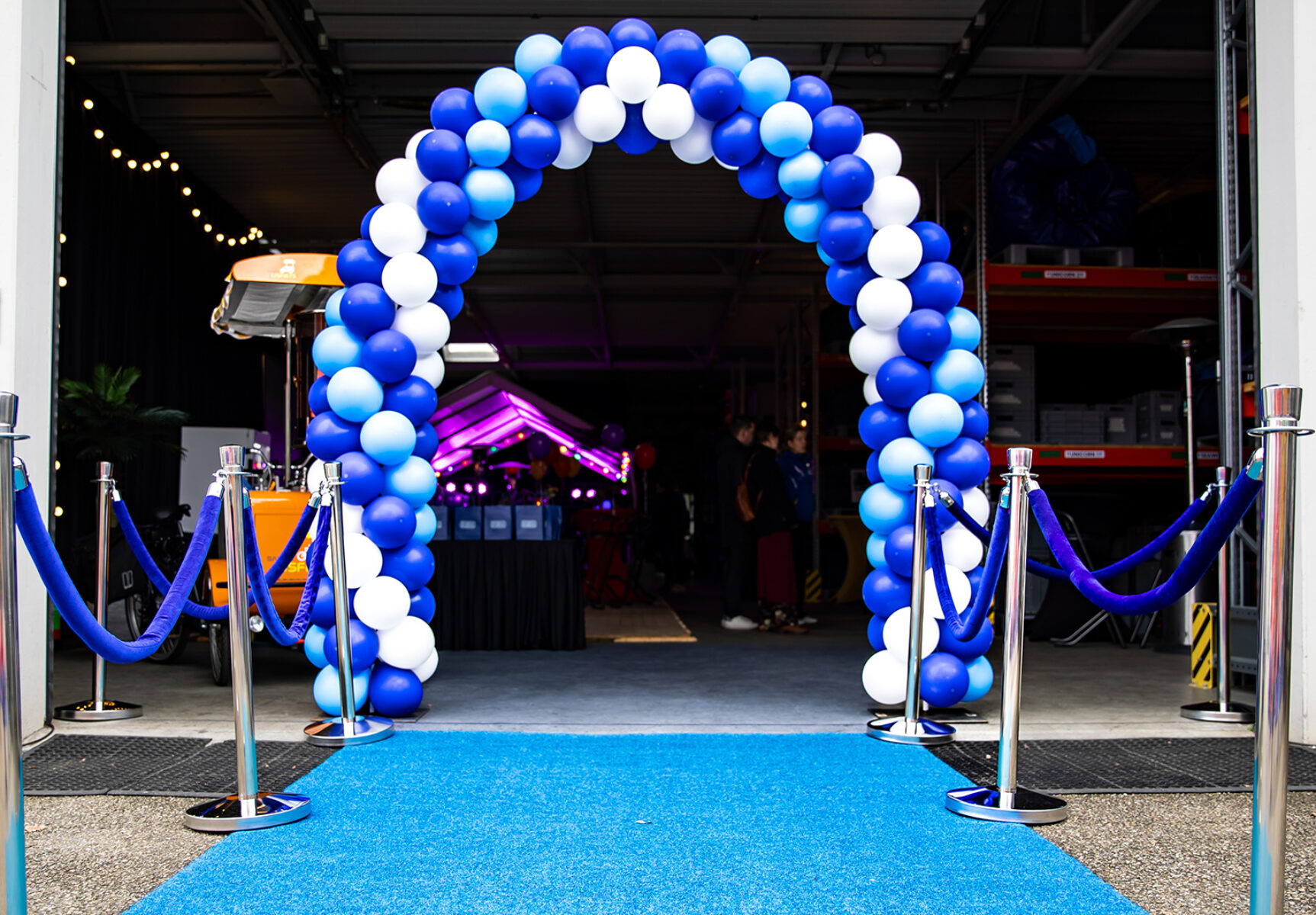 De ingang van de loods tijdens de Sanka Open Dag met een blauwe loper en ballondecoraties.