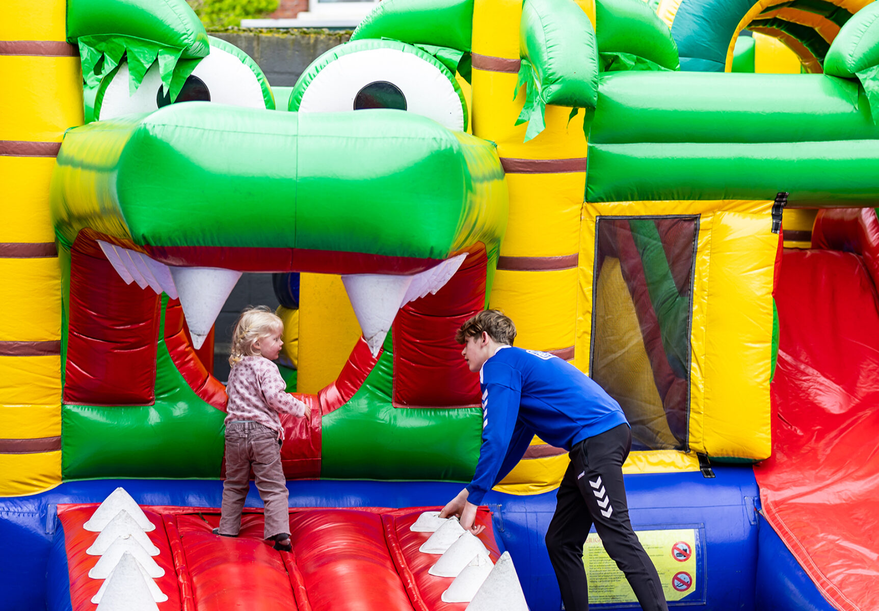 Een kind speelt op Springkussen Krokodil en wordt begeleid door een medewerker van Sanka Events.